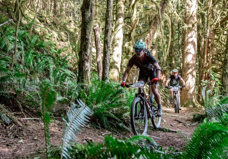 Brian racing a mountain bike through a forest